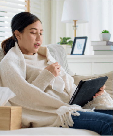 Woman wrapped in a blanket using a tablet for a virtual healthcare visit